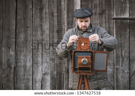 Photographer prepares for shooting and inserts film holder into retro large format camera. Concept - photography of the 1930s-1950s.