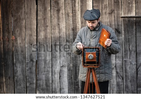 Photographer prepares for shooting and inserts film holder into retro large format camera. Concept - photography of the 1930s-1950s.