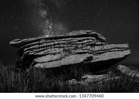 Black an white night Photo of Granite rocks an d slabs in Dartmoor with the milky way in background