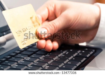 Photo of human hand holding the credit cart over black keyboard