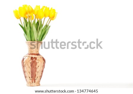 Yellow tulips in a wicker vase on a white background.