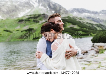 Beautiful bride and groom embrace and kiss in the mountains near the lake. Wedding photo session of a young couple in the mountains.