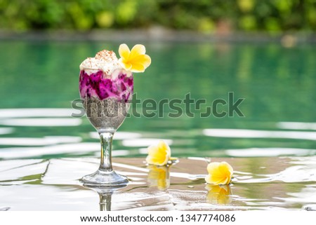 Chia seeds pudding with red dragon fruit and white yogurt in a glass for breakfast on the background of the swimming pool water, close up. The concept of healthy eating.