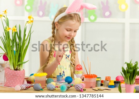 little child girl with Easter bunny ears painting Easter eggs at home. adorable child prepare for easter. Happy easter