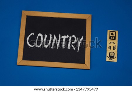 inscription COUNTRY on a black board with a blue background with three wooden cubes