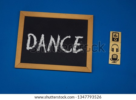 inscription DANCE on a black board with a blue background with three wooden cubes