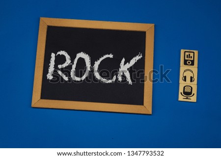 inscription ROCK on a black board with a blue background with three wooden cubes