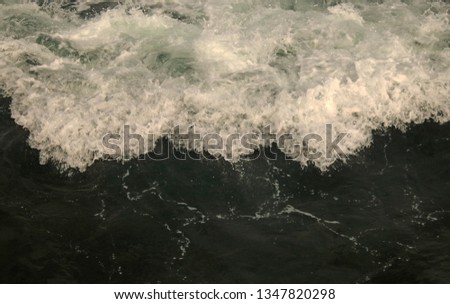 TURBULENT FOAM WAVE ON GREEN SEA WATER