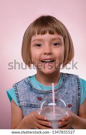 Little girl drinks milkshake on pink background