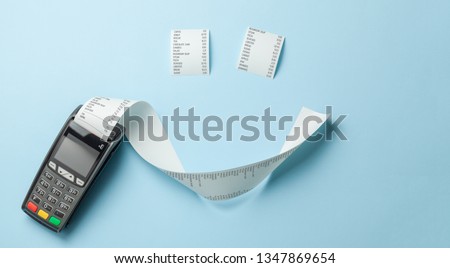 Terminal cash register machine POS for payments and long roll paper cash tape in the shape of smile on blue background Royalty-Free Stock Photo #1347869654