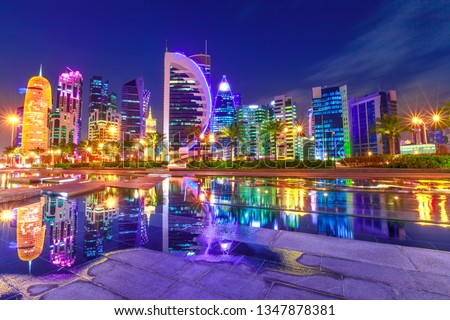 Capital of Qatar. Colorful Doha West Bay high rises illuminated at night reflections in downtown park. Scenic towers of Doha skyline, Middle East, Arabian Peninsula in Persian Gulf. Violet colors shot Royalty-Free Stock Photo #1347878381