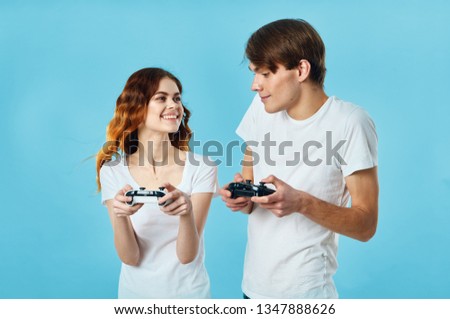 The guy and the girl play video games in their hands with gamepads a blue background
