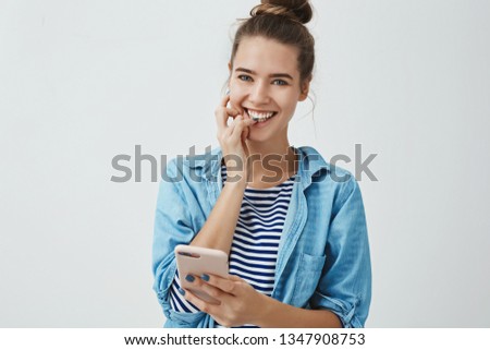 Gorgeous european 25s birthday girl feeling excited happy pleased receiving awesome bday messages holding smartphone smiling happily feeling lucky having devoted awesome friends, looking camera