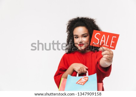 Portrait of a cheerful african woman standing isolated over white background, showing shopping bags, showing sale tag