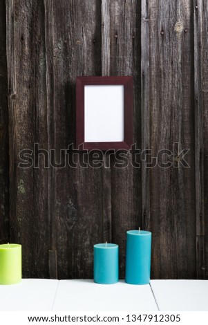 empty picture frame, candles on white table, old weathered wooden wall background