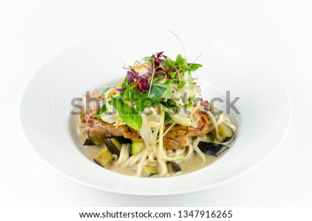 Fillet of sea bass with roasted eggplant and olives on a plate on a white background
