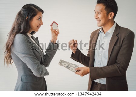 Real estate broker and customer shaking hands and pay after signing a contract: real estate, home loan and insurance concept.