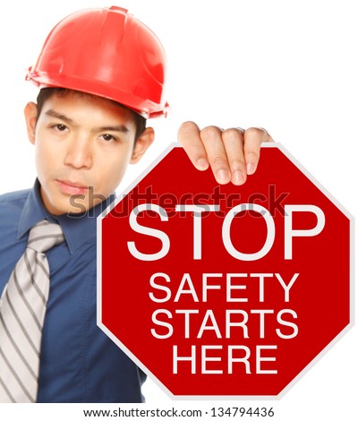 A man wearing a hardhat holding a Stop sign with a safety message (shallow depth of field)