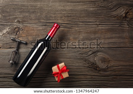 Holiday Dinner setting with red wine and gift on rustic wood in flat lay view.