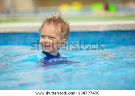 2 year old kid laughing in a swimming pool.