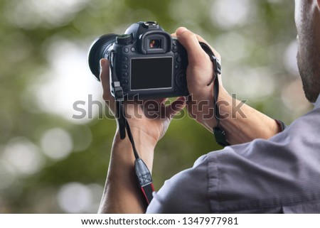 Young man holds modern digital black camera