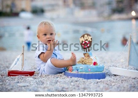 Sweet baby boy, celebrating on the beach first birthday with sea theme cake and sea decoration