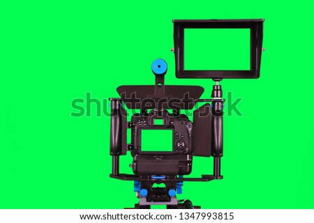 Dslr camera with additional screen for video shooting with green screen on the tripod isolated on green background. The chromakey. Green screen.