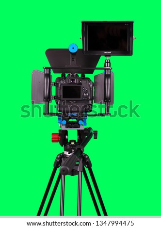 Dslr camera with additional screen for video shooting on the tripod, isolated on green background. The chromakey. Green screen.