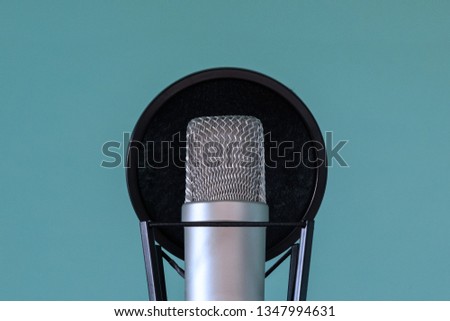 Professional studio microphone with pop filter and shock absorber on a blue background. Close-up. The concept of high-quality sound and voice recording. Copy space.