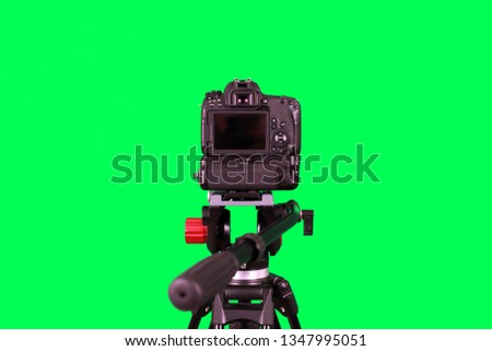 
Dslr camera with empty screen on the tripod, isolated on green background. The chromakey. Green screen.