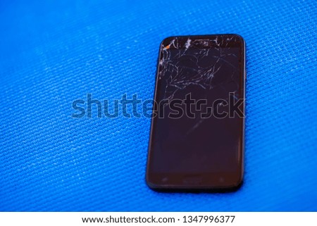 Mobile smartphone with broken screen on blue background.