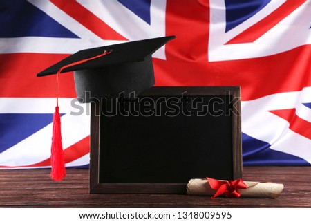 Graduation cap with blank frame and diploma on brown wooden table