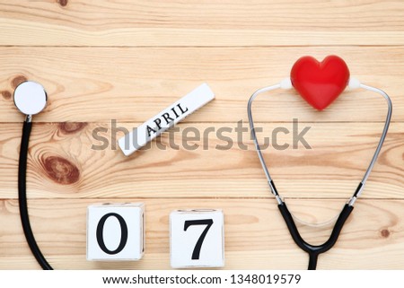 Stethoscope with red heart and cube calendar on wooden table