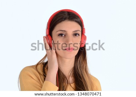 Beautiful young girl listening to music with red headphones in studio.