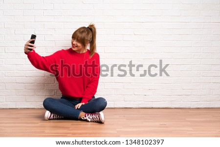 Redhead woman siting on the floor making a selfie
