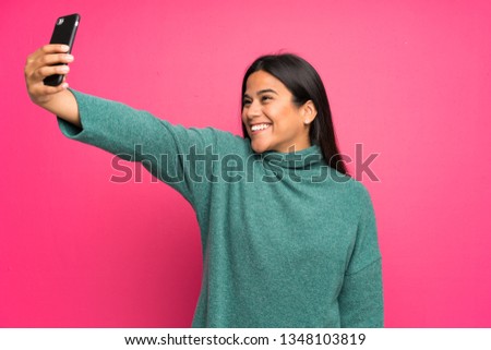 Young Colombian girl with green sweater making a selfie