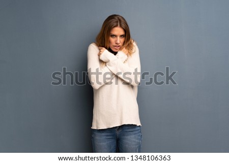 Blonde woman over grey background freezing