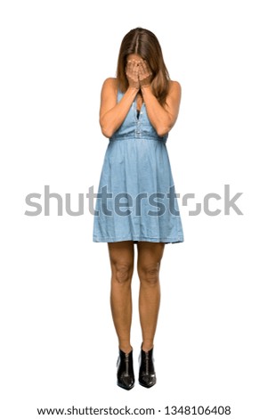 A full-length shot of a Blonde woman with jean dress with tired and sick expression over isolated white background