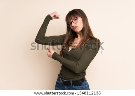Young woman on ocher background doing strong gesture