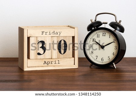 Wood calendar with date and old clock. Friday 30 April
