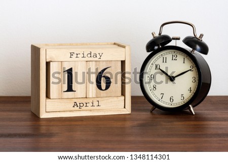 Wood calendar with date and old clock. Friday 16 April