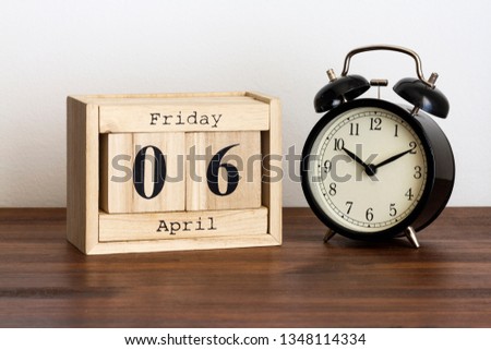 Wood calendar with date and old clock. Friday 6 April