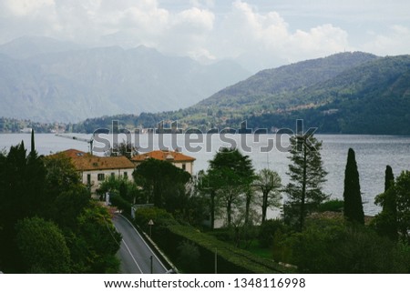 Scenery with Lake Como, medieval buildings and mountains on background on a cloudy day