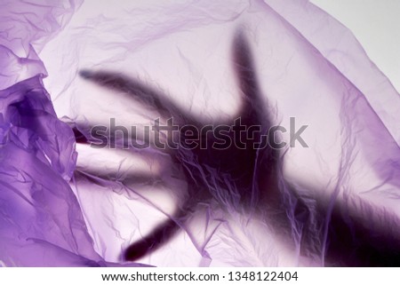 Dead hand in plastic bag. Murder concept. Puple color background.