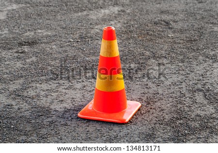Red and yellow striped warning cone on asphalt road