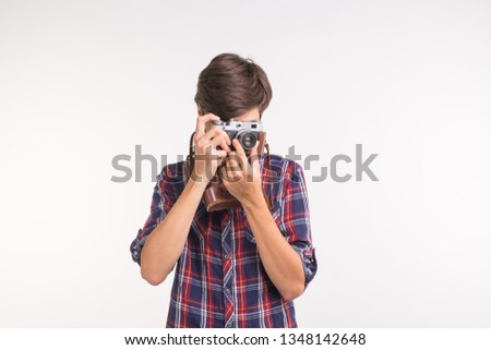 People hobby and leisure concept - young hipster man using his vintage camera on white background