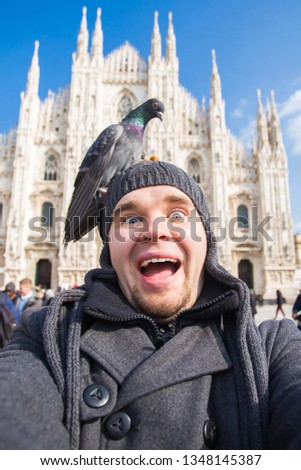 Italy, excursion and travel concept - funny guy taking selfie with pigeons in front of cathedral Duomo in Milan