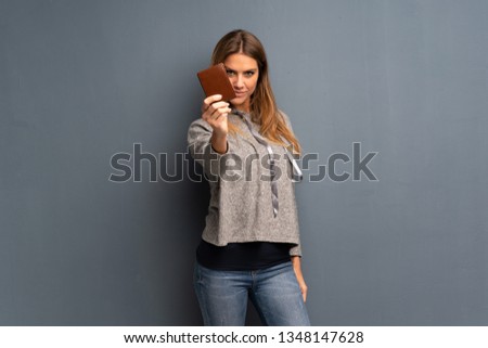 Blonde woman over grey background holding a wallet
