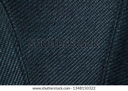 Close up fabric texture of upholstered luxury armchair. Premium stitching and crosshatched pattern on sofa surface. Dramatic lighting of subject material.