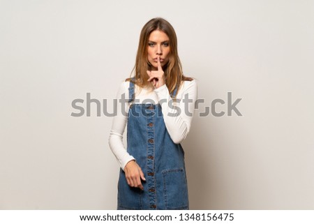 Beautiful woman over isolated white wall showing a sign of silence gesture putting finger in mouth